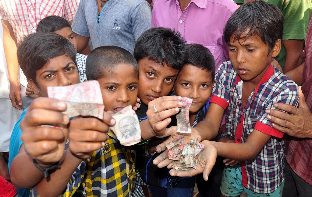 Children showing torn notes of Rs 500 and Rs 1,000 found near a drain in Guwahati. Photo; UNI