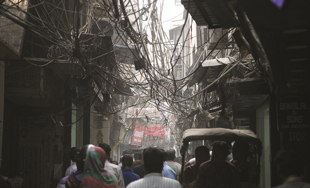 A mesh of wire cables hanging over shoppers in a narrow lane in Old Delhi. Photo: Anil Shakya