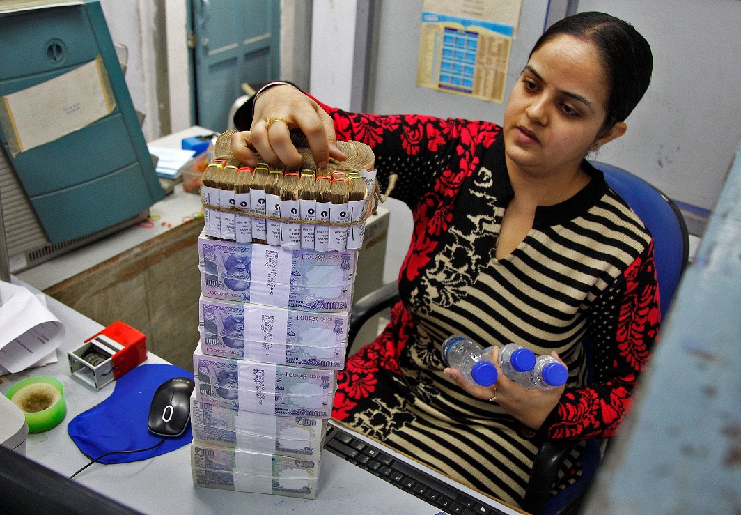 A cashier stacks Indian currency notes inside a bank in Chandigarh. Photo: UNI