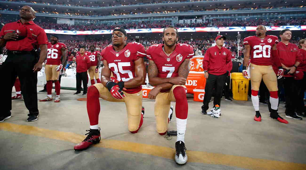 Football player Colin Kaepernick (without cap) kneeling during the anthem to protest the shooting of African-Americans by police officers