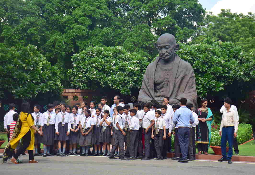 YOUNG MINDS: School students visiting Parliament house pose for a photograph in front of the Gandhi statue, in New Delhi, UNI
