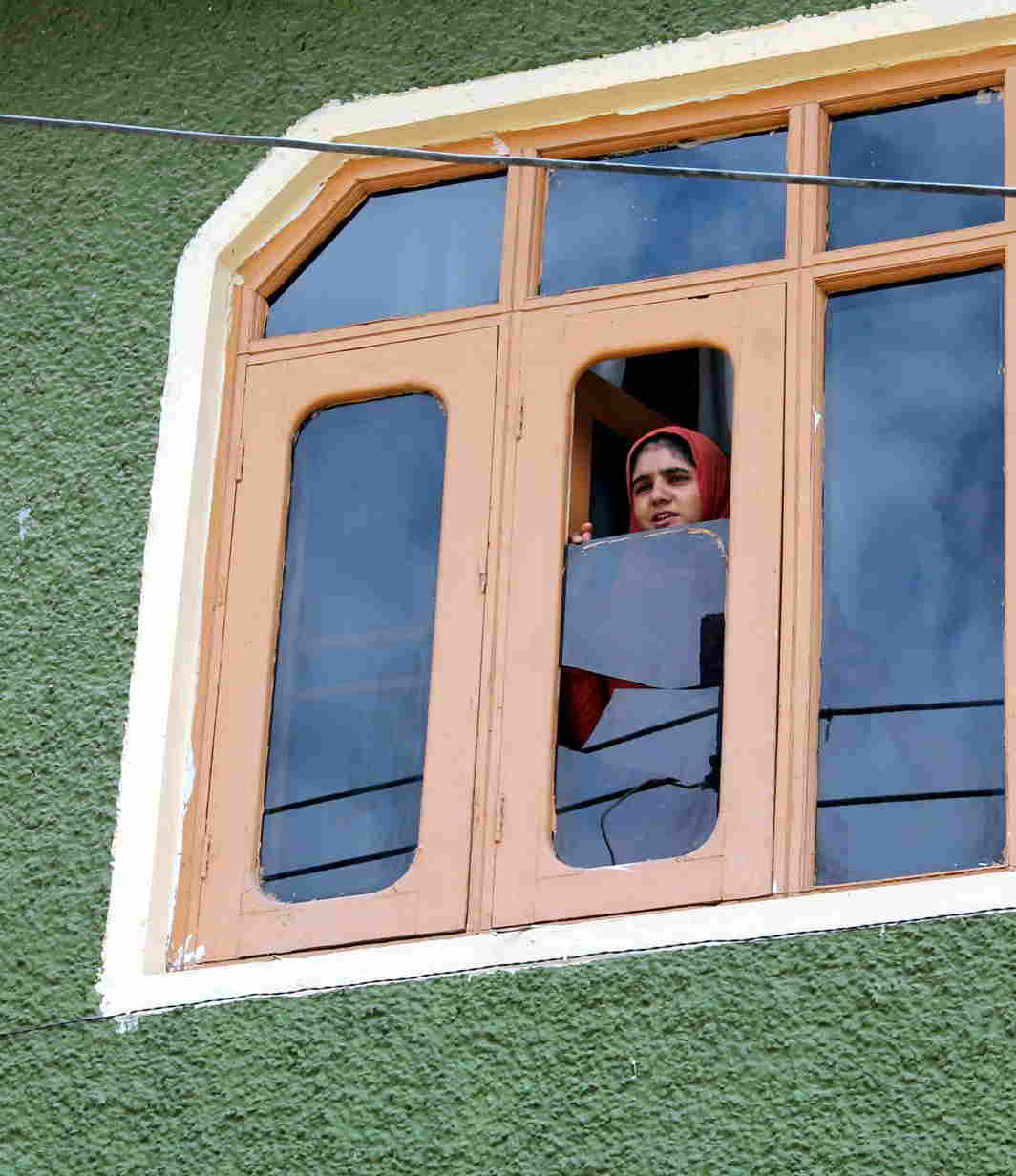 SILENT SENTINEL: A girl peeps through a window during raids by the National Investigation Agency in connection with a terror funding case, in Srinagar, UNI