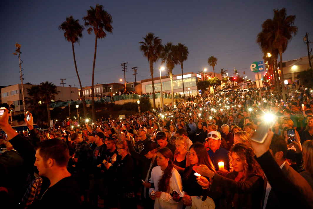 IN DEFIANCE: People hold candles and flashlights into the air during a memorial for Rachael Parker and Sandy Casey, Manhattan Beach city employees and victims of the October 1st Las Vegas Route 91 music festival mass shooting, in Manhattan Beach, California, Reuters/UNI