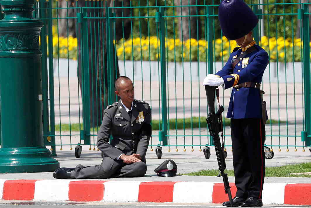 BOW TO STATURE: A royal guard and a policeman show their respect during a procession to transfer the royal relics and ashes of Thailand's late King Bhumibol Adulyadej from the crematorium to the Grand Palace in Bangkok, Thailand, Reuters/UNI