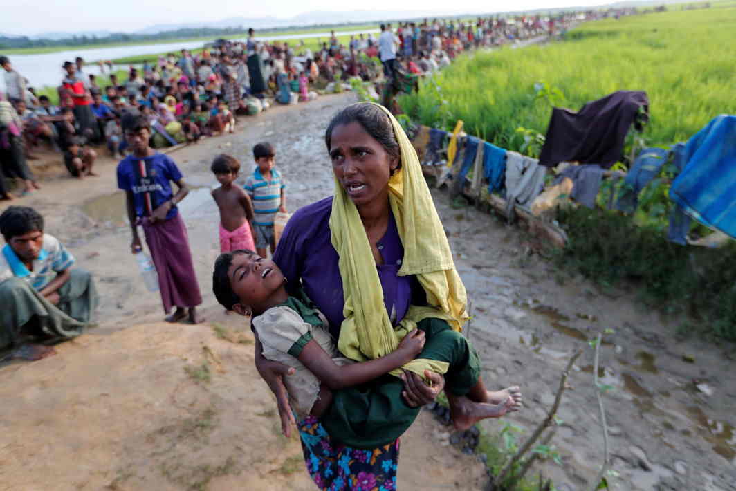 IN DESPAIR: A Rohingya refugee woman who crossed the border from Myanmar a day before carries her daughter and searches for help as they wait to receive permission from the Bangladeshi army to continue their way to the refugee camps, in Palang Khali, Bangladesh, Reuters/UNI