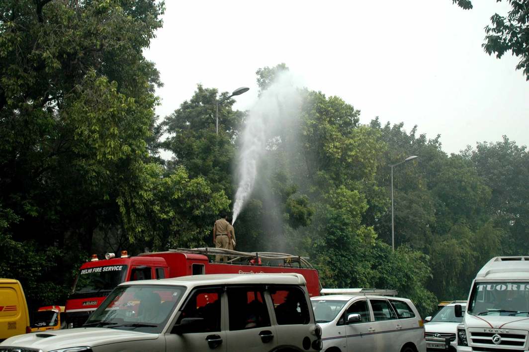 FIGHTING POLLUTION: Delhi Fire Services personnel sprinkle water on trees to settle the dust near India Gate, UNI
