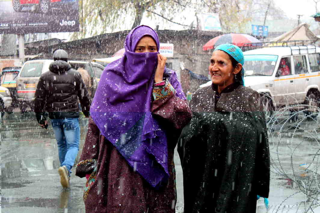 PHERAN QUEENS: Kashmiri women dressed traditionally walk down the Exchange Road in Srinagar, amid snowfall, UNI
