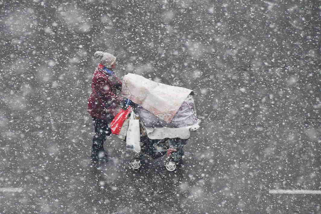 MERCURY DROP: A woman pushing a stroller walks in the snow in Yantai, Shandong province, China, Reuters/UNI