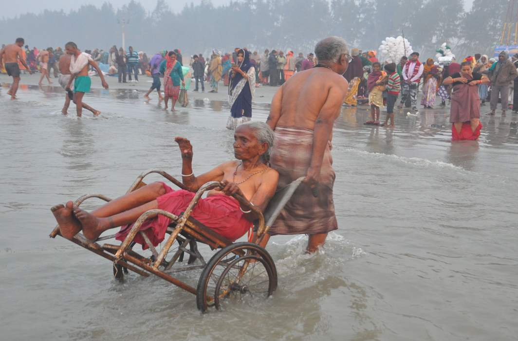MOTHER I LOVE YOU: An elderly man helps his wheelchair-bound nonagenarian mother take a dip in the Ganga at Sagar Island, UNI