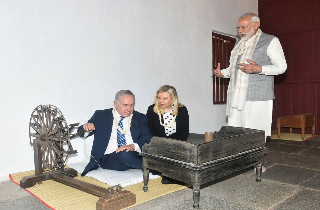 IN HIS SEAT: Prime Minister of Israel Benjamin Netanyahu tries his hand on the spinning wheel during his visit to Sabarmati Ashram in Ahmedabad. Prime Minister Narendra Modi also seen, UNI