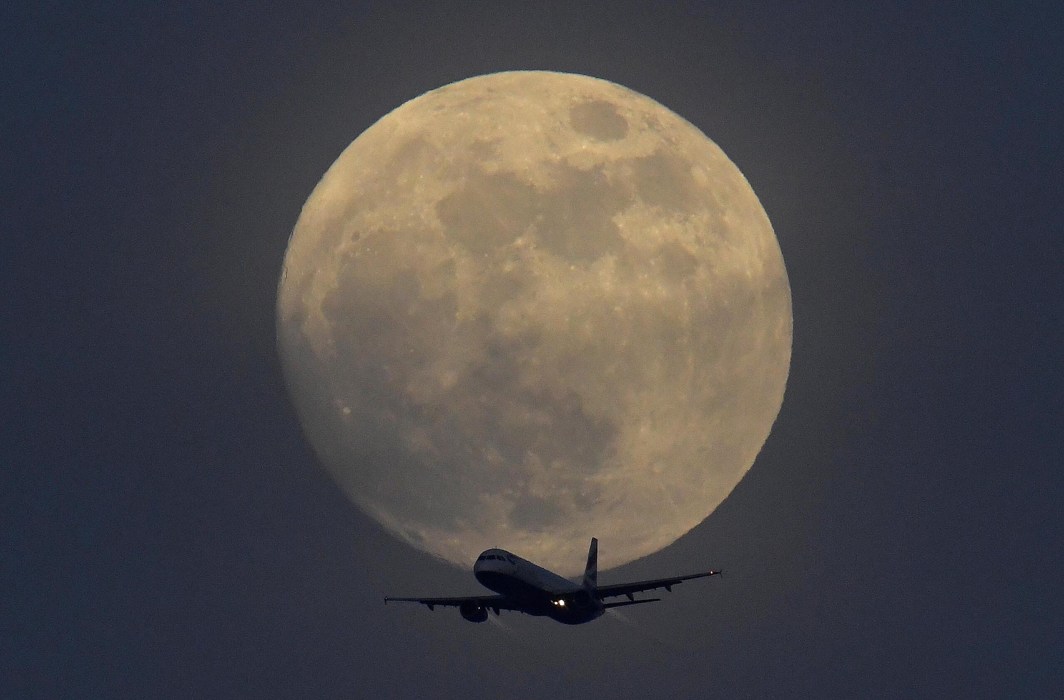FLY AWAY: A British Airways aircraft flies in front of a full moon over London, Britain, Reuters/UNI