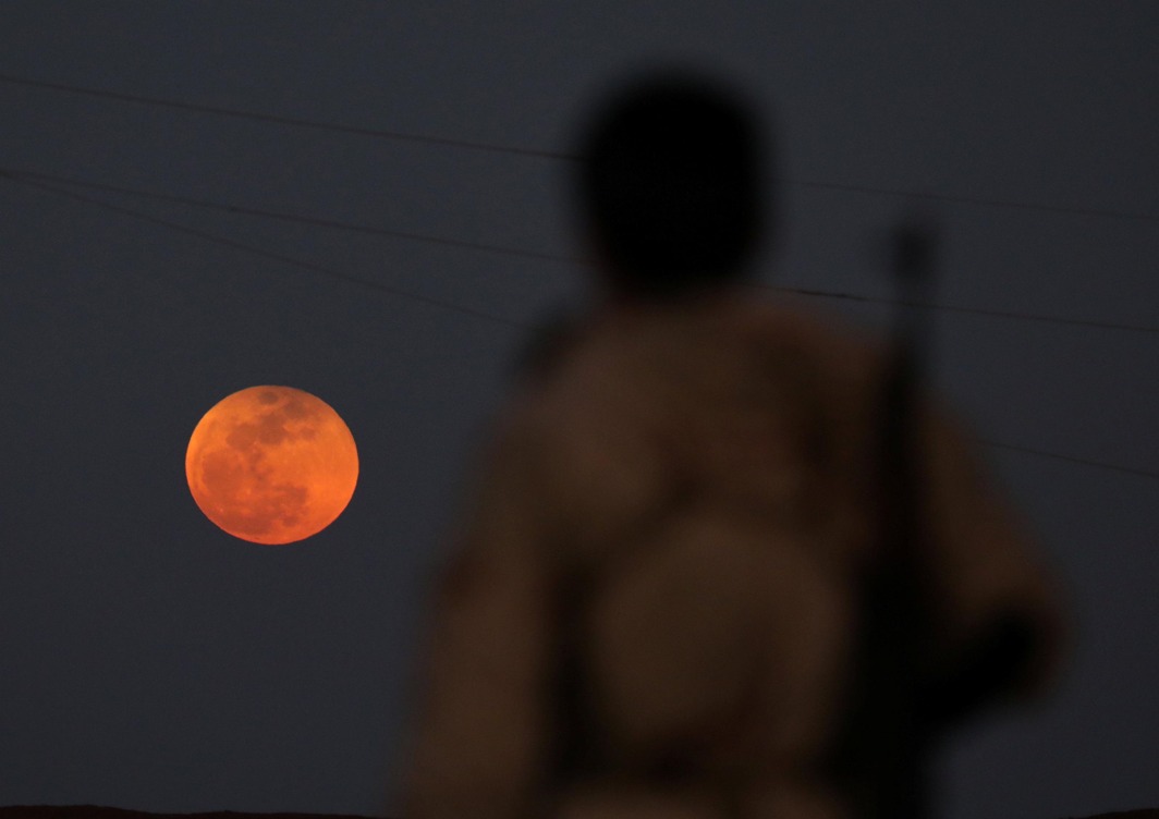 AND THE BIG FALL DOWN: A fighter from Free Syrian Army is seen watching a full moon rising in Daraa, Syria, Reuters/UNI